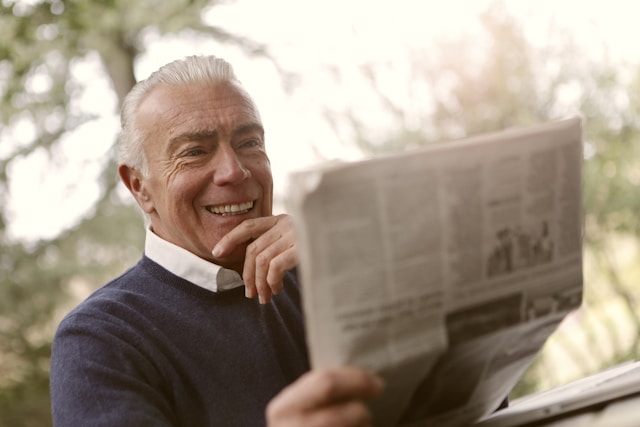 elderly man reading a paper outside