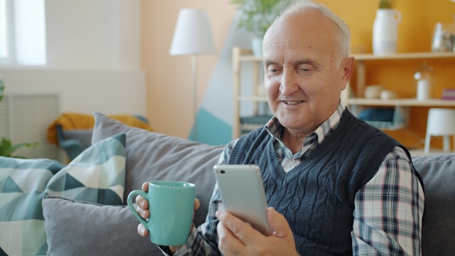 elderly resident smiling with a coffee on a video call to family 