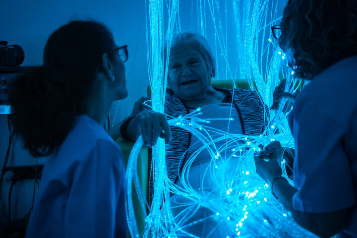 sensory room with older woman enjoying playing with the lights