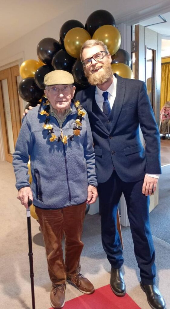 staff walking with resident down the red carpet