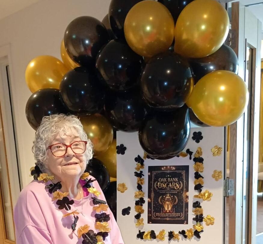 resident at the red carpet of the event at care home with balloons around her